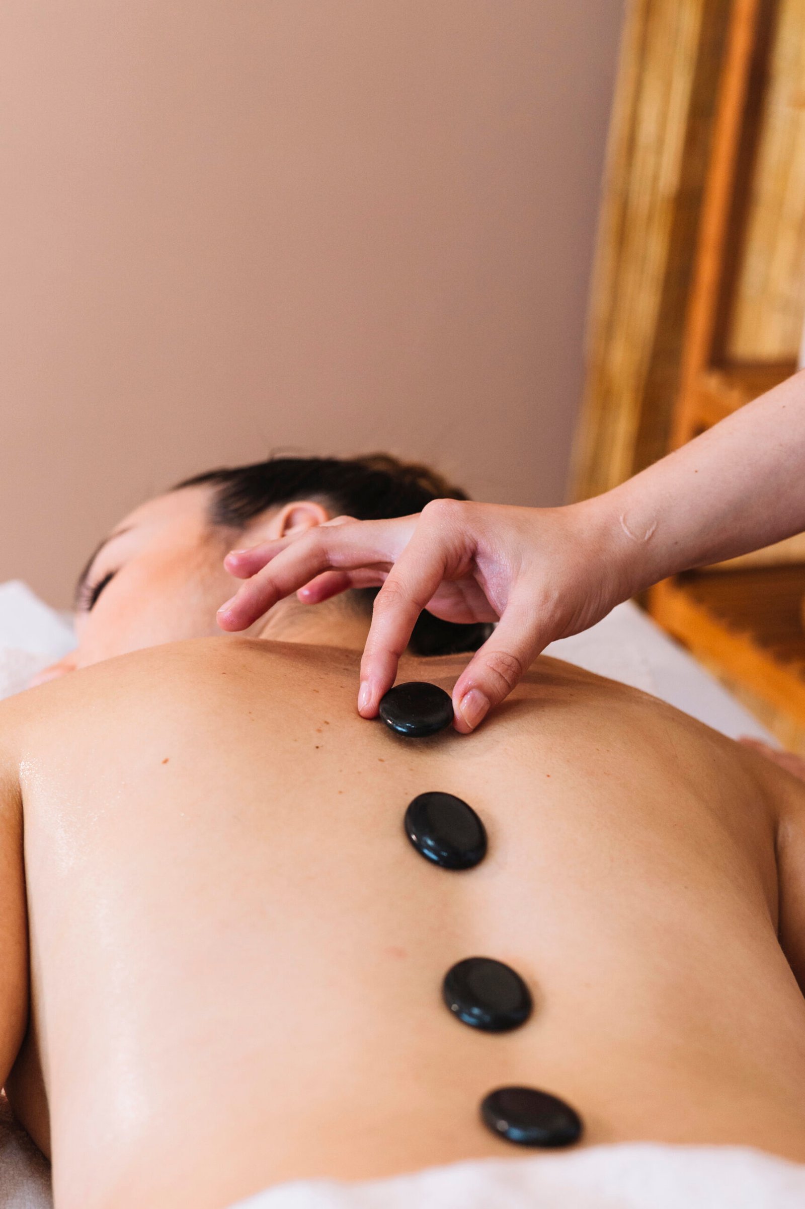 Person receiving a Chinese style full-body massage with hot stones placed along the spine, promoting relaxation and energy flow. Mutao Wellness Spa
